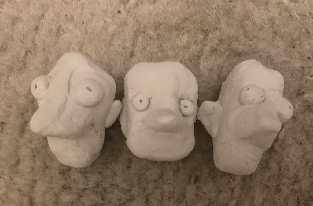 Three clay modeled faces by Derin Oesch